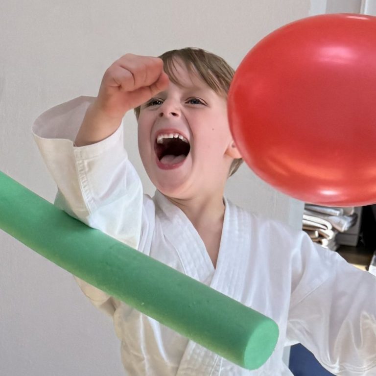 Lachendes Kind beim spielerischen Karatetraining bei YUNARI